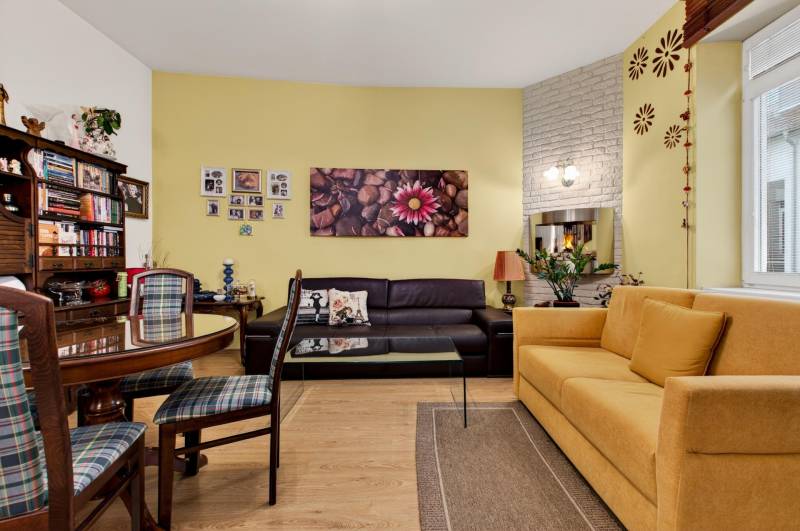Living room in a 3-room apartment with wooden decor flooring and comfortable seating.