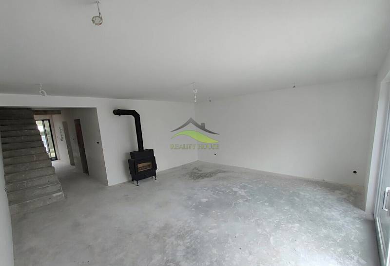 Interior of a family house with a fireplace and staircase, awaiting completion.