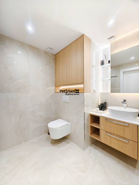 Bathroom with wood-patterned flooring in a 2-room apartment, light tiles and a wall-hung toilet.