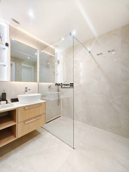 Bathroom in a 2-room apartment with a large mirror and a glass shower enclosure.