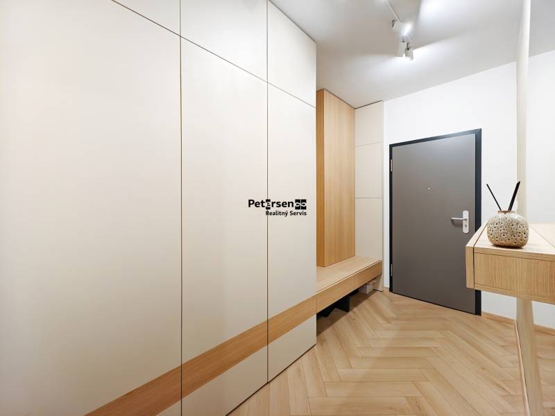 Entrance hallway with wood-patterned flooring in a 2-room apartment with white cabinets.