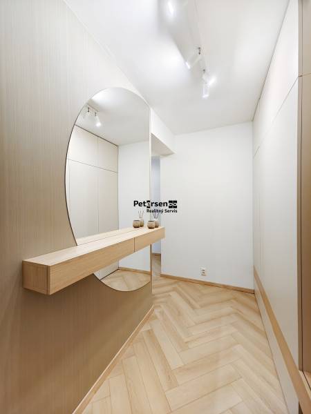 Entrance hall with wood-patterned flooring and a large mirror in a 2-room apartment.
