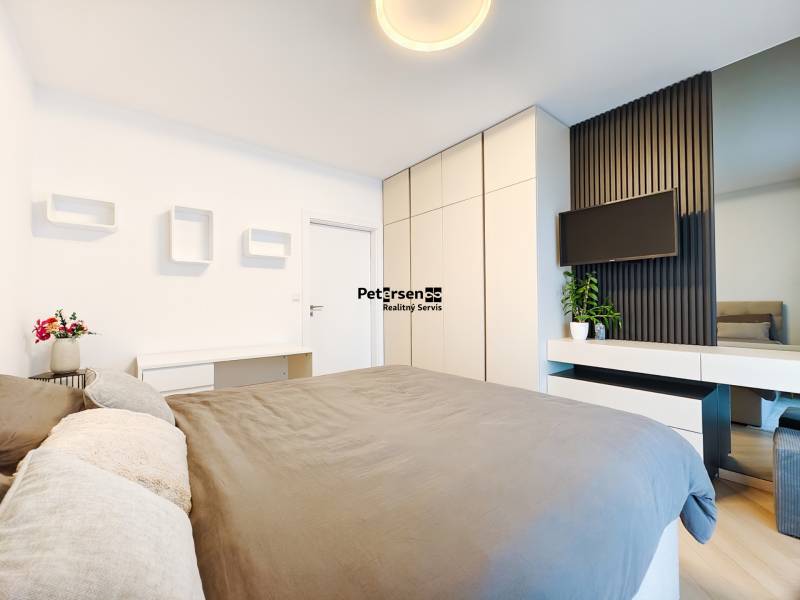 Bedroom in a 2-room apartment with a bed, wardrobe, and a TV on the wall.