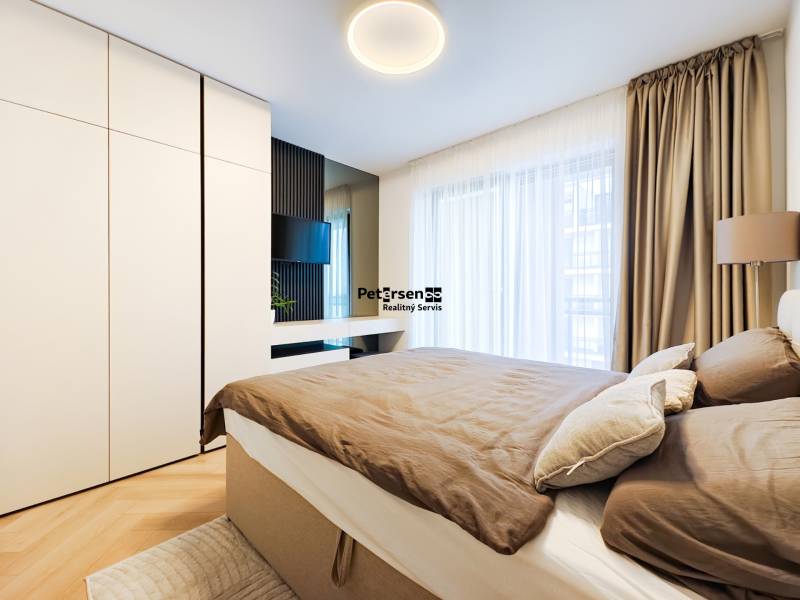 Bedroom in a 2-room apartment with wood-patterned flooring, a large wardrobe, and curtains.