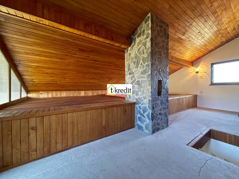 An attic room with wooden paneling and a stone chimney in a cottage.