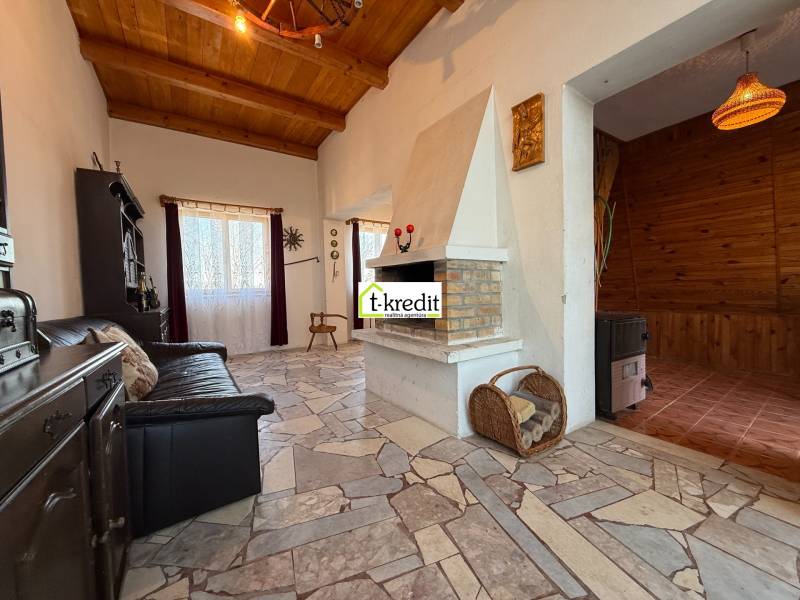 A cottage with a fireplace, a comfortable sofa, and a wooden-patterned floor.