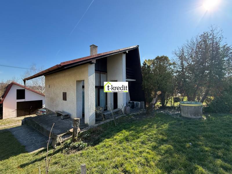A cottage in Zlaté Moravce surrounded by a garden and lawn under a clear sky.
