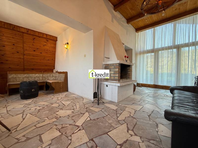 Interior of a cabin with a fireplace and seating, stone floor.