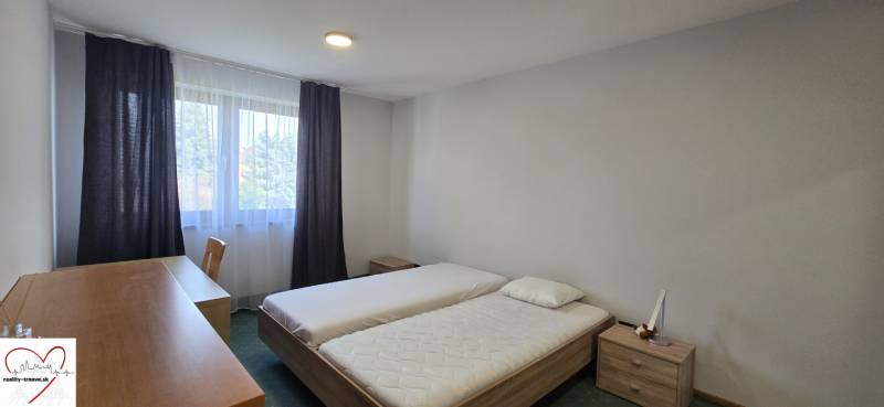 A bedroom with two beds, a desk, and a window in a three-room apartment.
