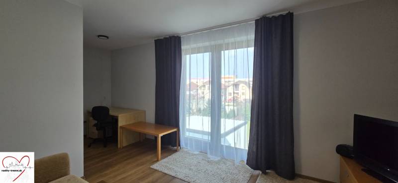 Living room with a table and wood-patterned flooring in a 3-room apartment.