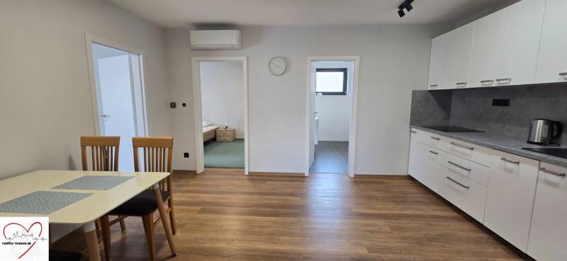A kitchen in a 3-room apartment with a wooden decor floor and a dining table.