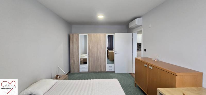 A room in a 3-room apartment with a bed, wardrobe, air conditioning, and wooden decor furniture.