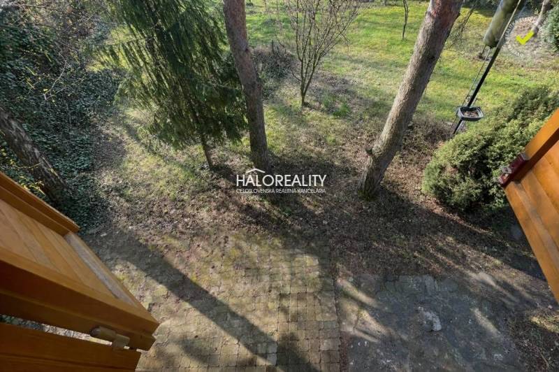 In Úľany nad Žitavou, there is a garden with paving and trees near the cottage.
