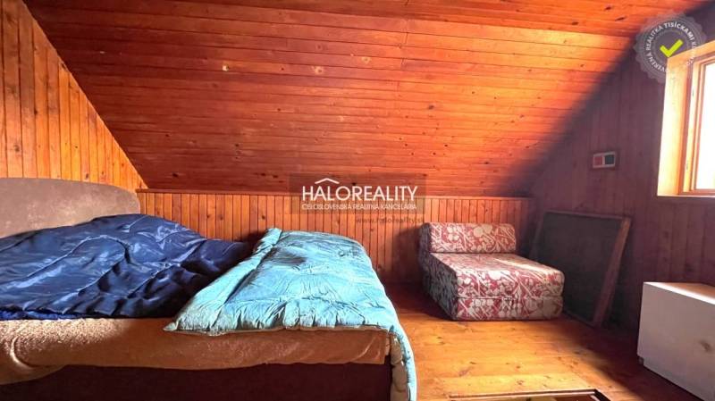 Attic room in a cottage with wooden paneling and two beds.
