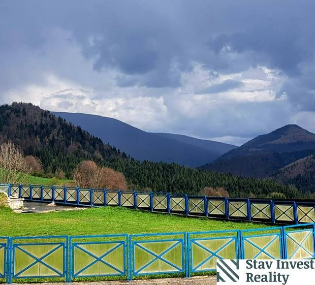 Mountain scenery in Donovaly with a blue wooden fence and forests in the background.
