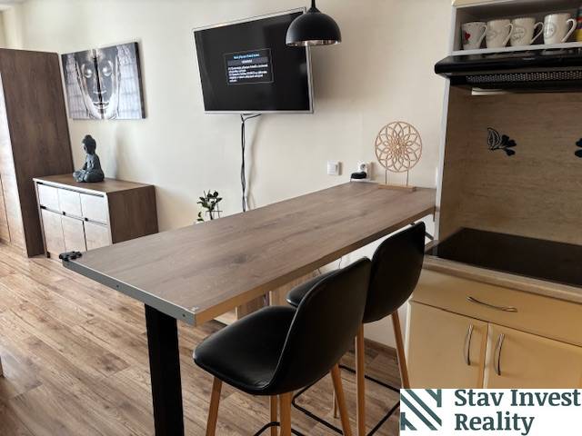 A dining counter in a studio apartment with a wood-patterned floor and modern furniture.