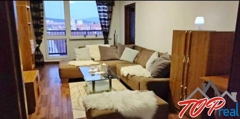 Living room in a three-room apartment with a sofa, glass table, and a view from the window.