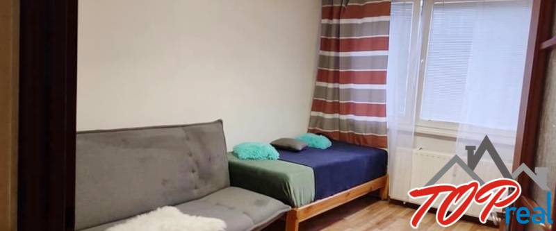 A room in a 3-room apartment with a sofa and a bed, near the window.