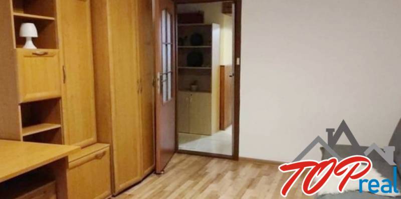 Wooden furniture in a 3-room apartment with parquet flooring and open shelves.
