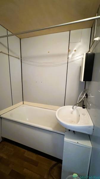 Bathroom in a 3-room apartment with a bathtub, sink, simple tiles, and a bathroom cabinet.