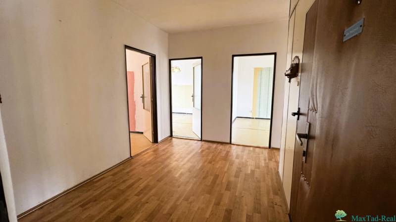 Entrance hall in a 3-room apartment with a wooden decor floor and multiple doors.