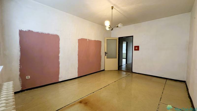 A room with unique walls and a wooden decor floor in a 3-room apartment.