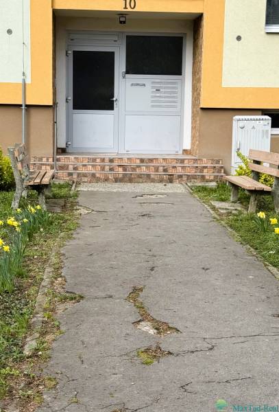 Entrance to the building on Škultétyho Street in Trebišov with benches and flower beds.