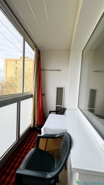 Glazed loggia in a 3-room apartment with a table and a plastic chair.
