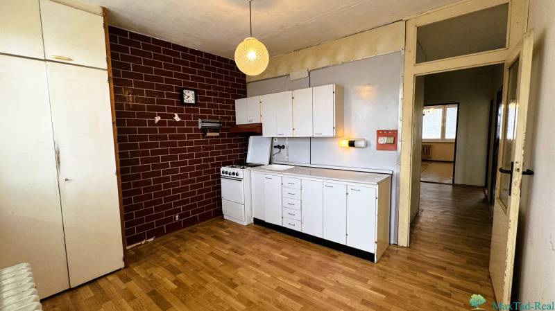 A kitchen in a 3-room apartment with white cabinets and a wood-patterned floor.