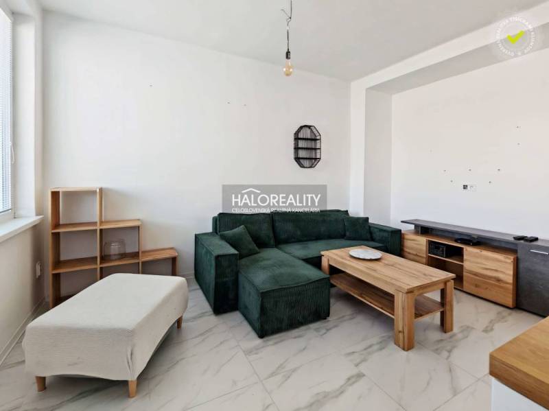 Living room with a dark sofa in a 3-room apartment with tiled flooring and wooden decor furniture.