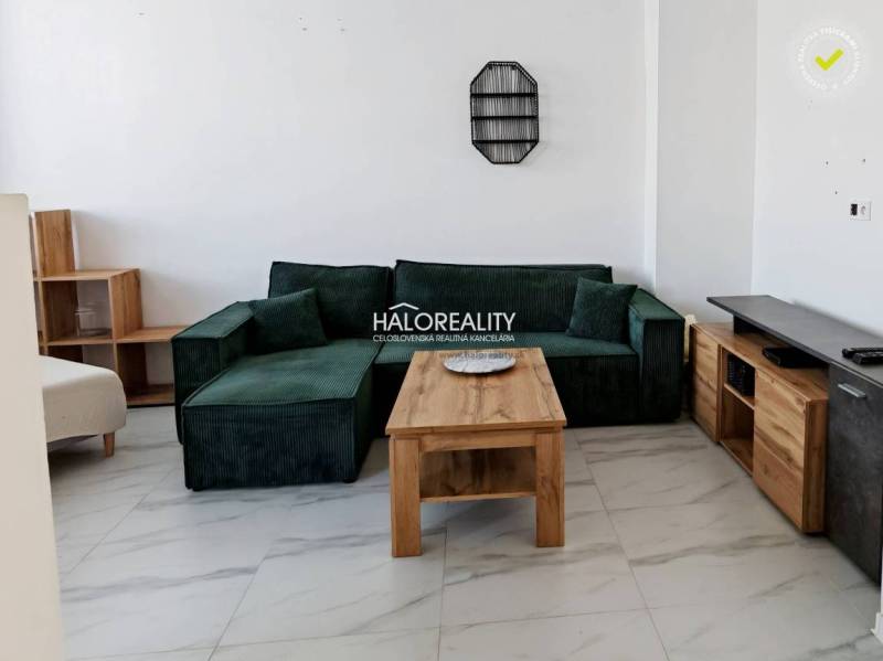 Living room in a three-room apartment with a green sofa and a wooden table.