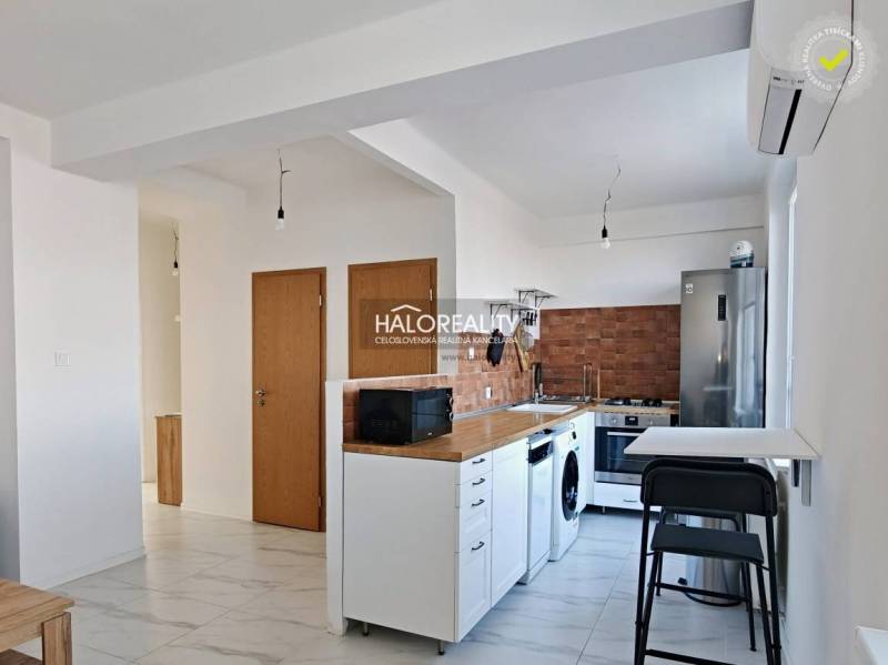A kitchen in a 3-room apartment with white cabinets, appliances, and wooden decor.
