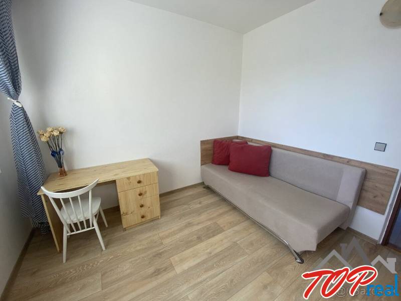 Living room in a 4-room apartment with a table, chair, and sofa. Floor with wood decor.
