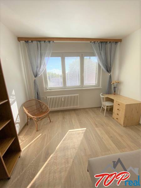 A bright room in a 4-room apartment with a wooden decor floor and a work corner.