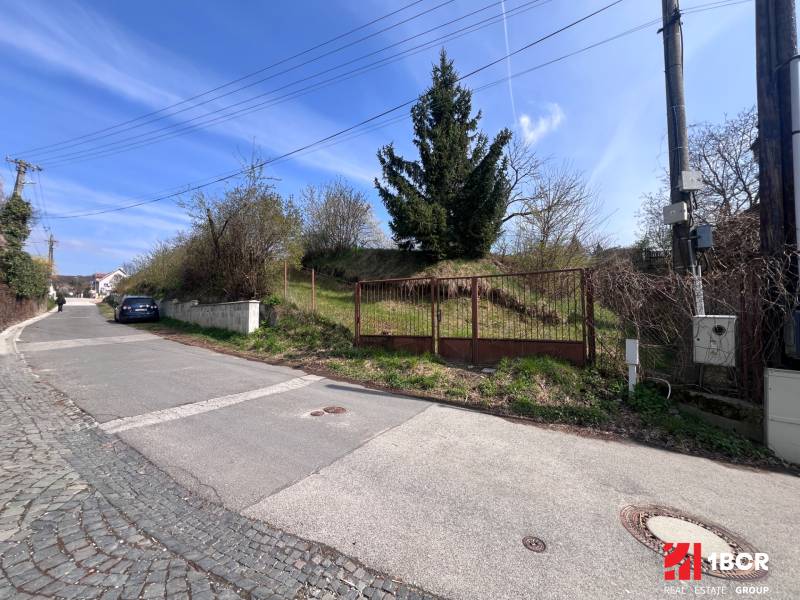 Building plot on Budovateľská Street in Marianka with a gate and access road.