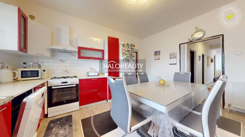 A family house kitchen with red cabinets, a dining table, and a wood-patterned floor.