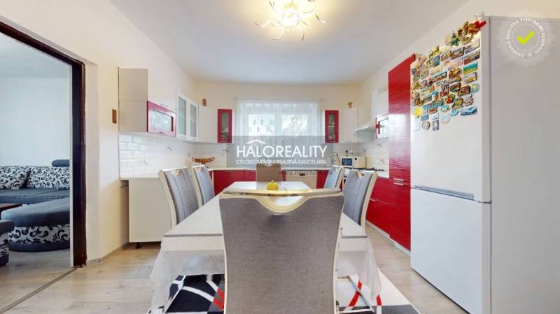 A kitchen in a family house with a red kitchen unit and a dining table.