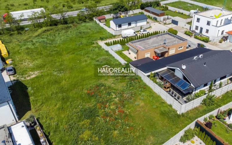 A view of grassy residential plots in Senec, surrounded by family houses.