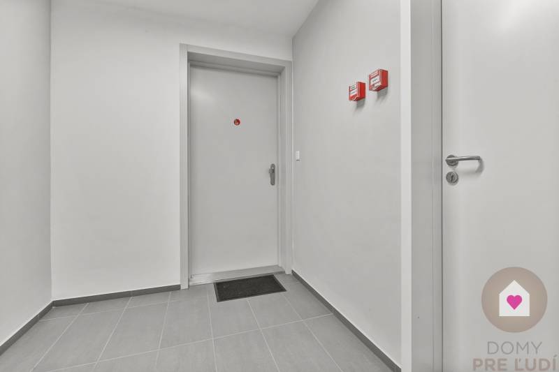 Hallway with doors, light gray walls, and tiles in a studio apartment.