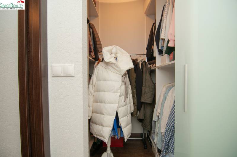 A wardrobe in a 2-room apartment with shelves and coats, a floor with a wooden decor.