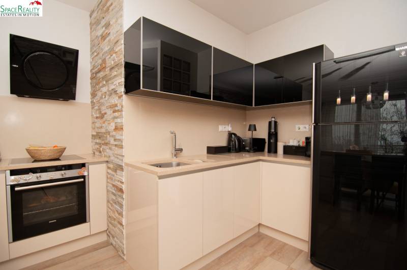 A kitchen in a 2-room apartment with stone cladding and a wooden decor floor.