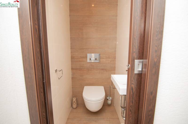 A toilet with a wall-hung WC and wood-effect tiles in a 2-room apartment.