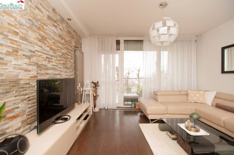 Living room in a two-room apartment with a stone wall and a wooden decor floor.
