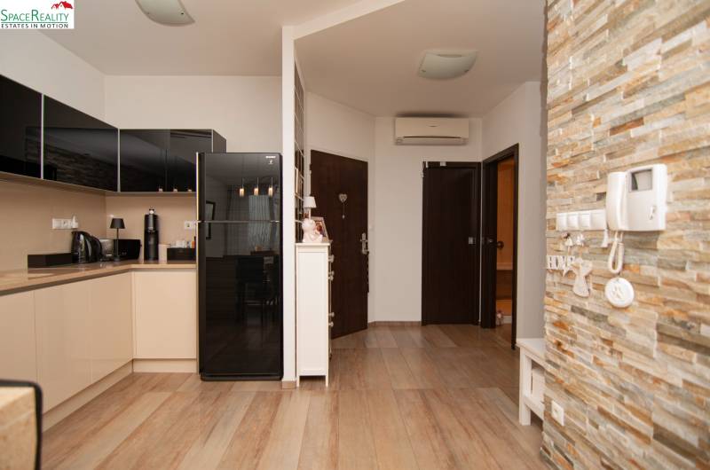 A kitchen in a 2-room apartment with a wooden decor floor and stone wall cladding.