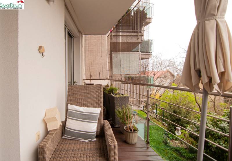 A balcony with a rattan chair and plants in a 2-room apartment.