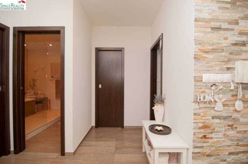 A hallway with stone cladding and a wooden decor floor in a 2-room apartment.