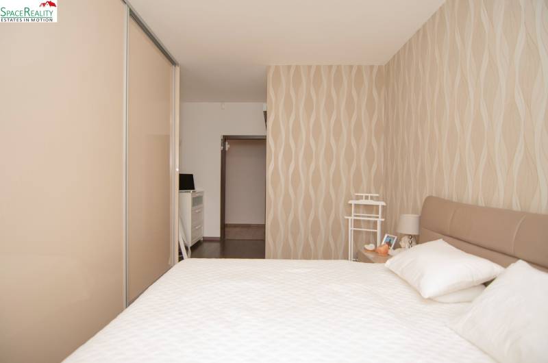 A bedroom in a 2-room apartment with wallpaper and a wardrobe in cream shades.