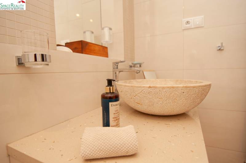 A natural stone sink in the bathroom of a two-room apartment with accessories.