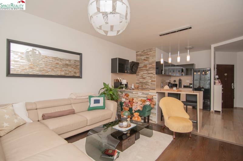 Living room with a beige sofa, chimney cladding column, and wooden decor flooring.