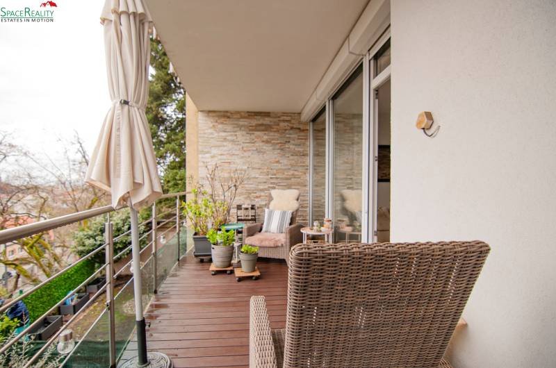 A balcony with a wooden decor floor and wicker furniture in a 2-room apartment.